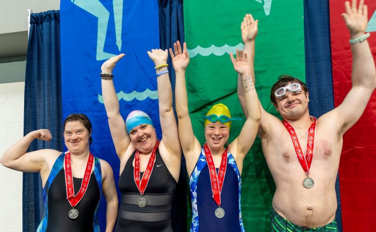 Four Special Olympics swimmers celebrate with their medals