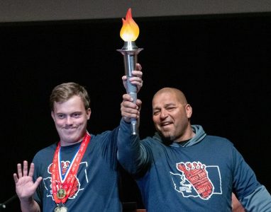 Two Special Olympics male athletes carry a torch